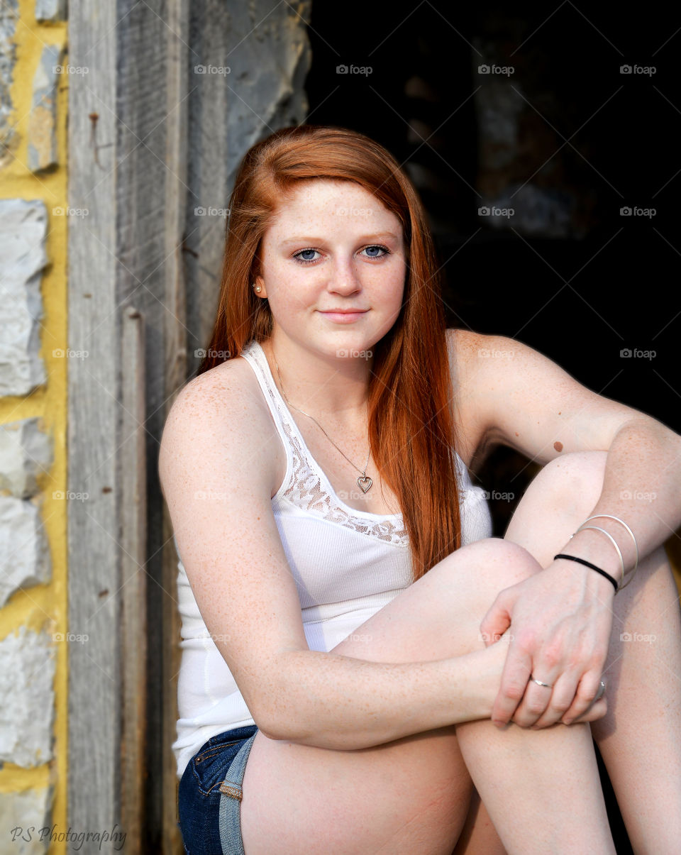senior photo. young girl poses in barn window