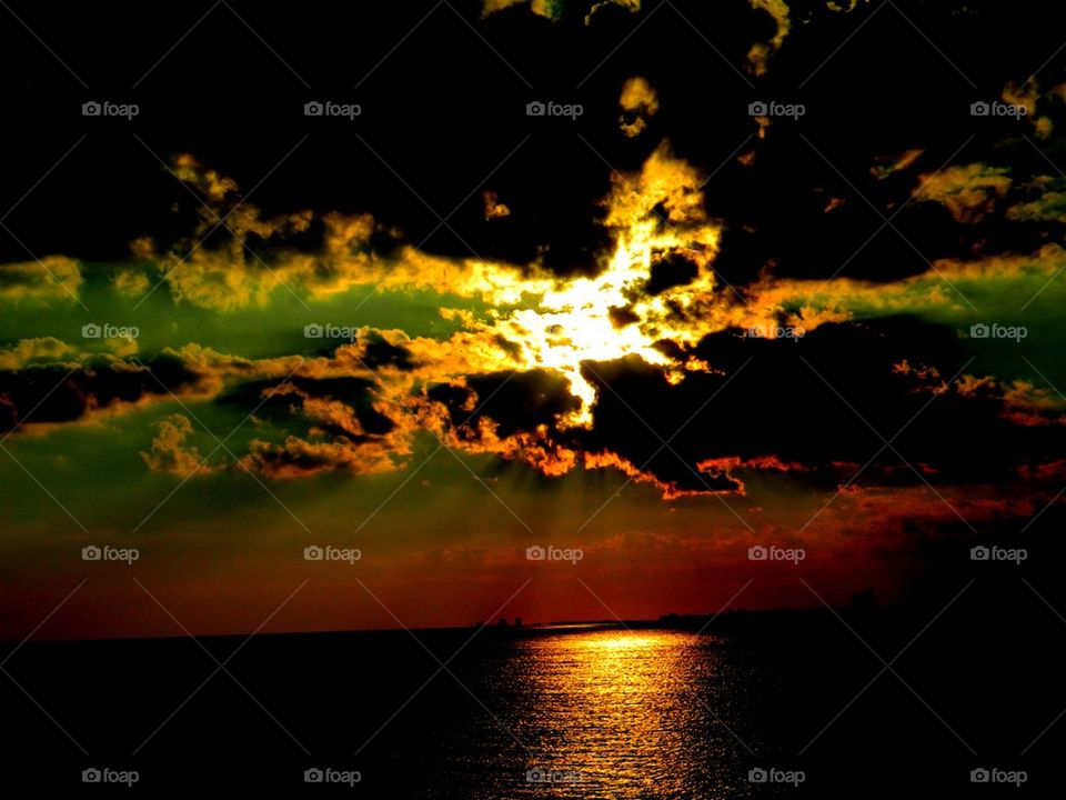 Angry Clouds. Beautiful sunset appears on the bay after a rain storm. The reflection is radiated across the bay in a shimmering path!