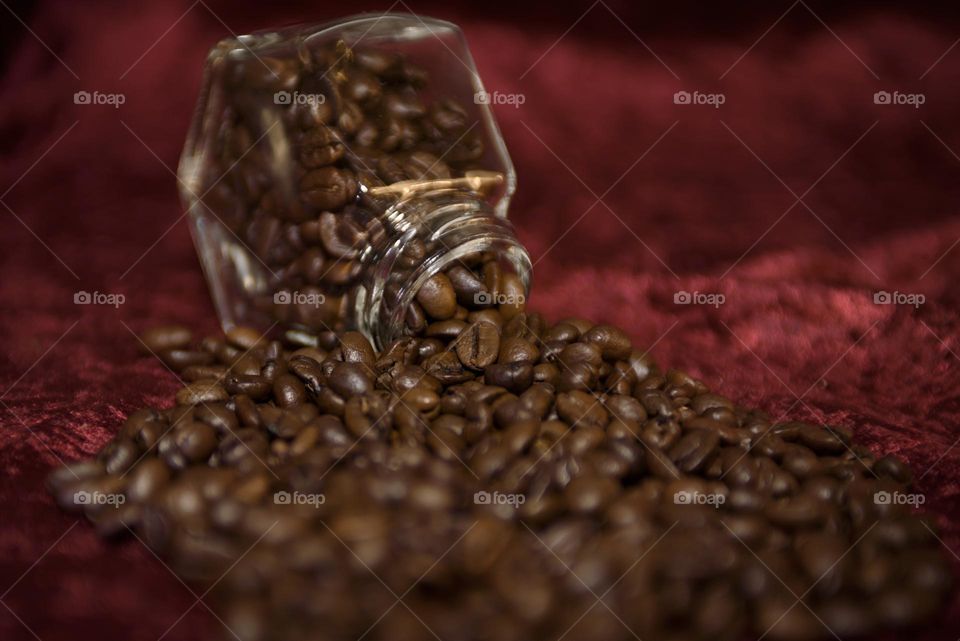 Fragrant coffee beans are scattered on a red background. Roasted coffee beans close up.