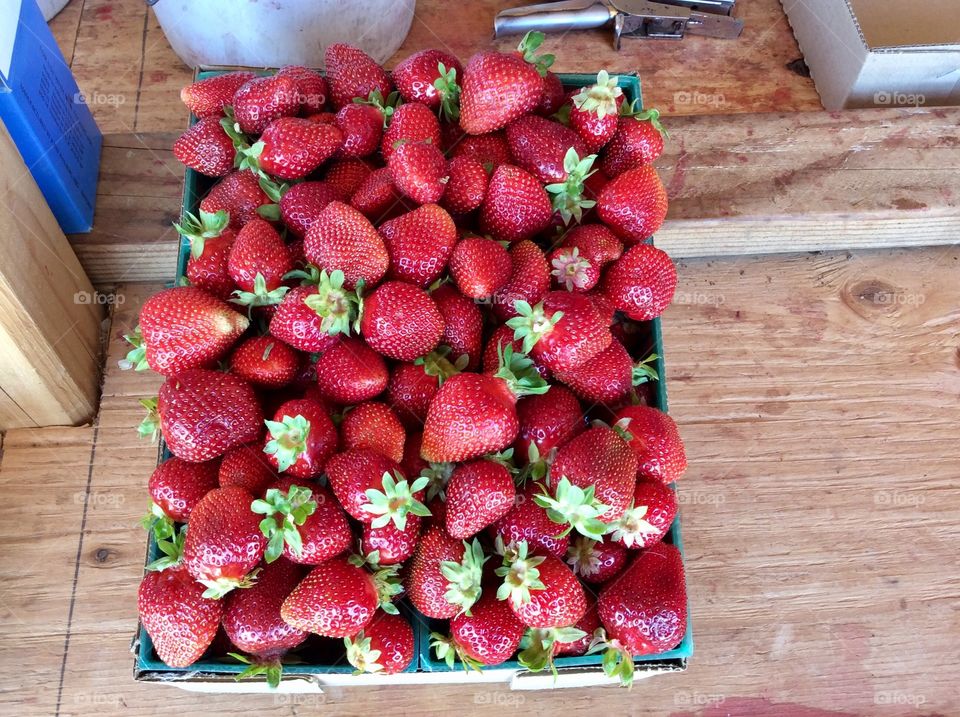 Fresh picked basket bright red strawberries, hulls on,  at market, resting on wood shelf, country 