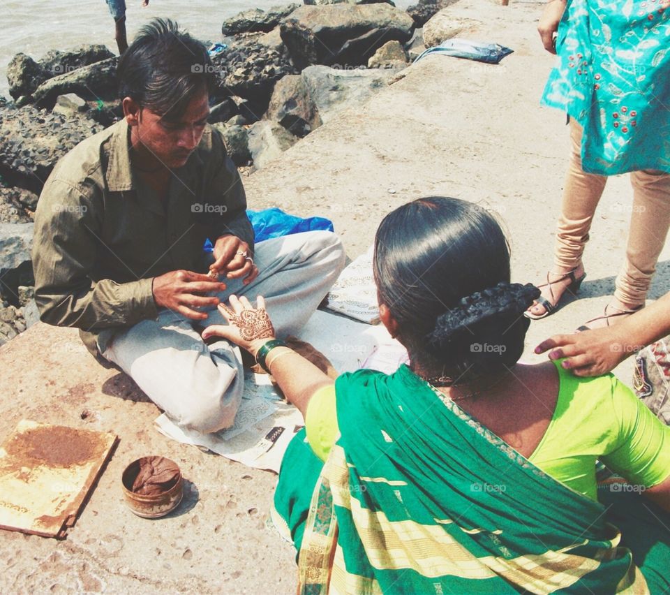 Women having henna tattoo done on he hand