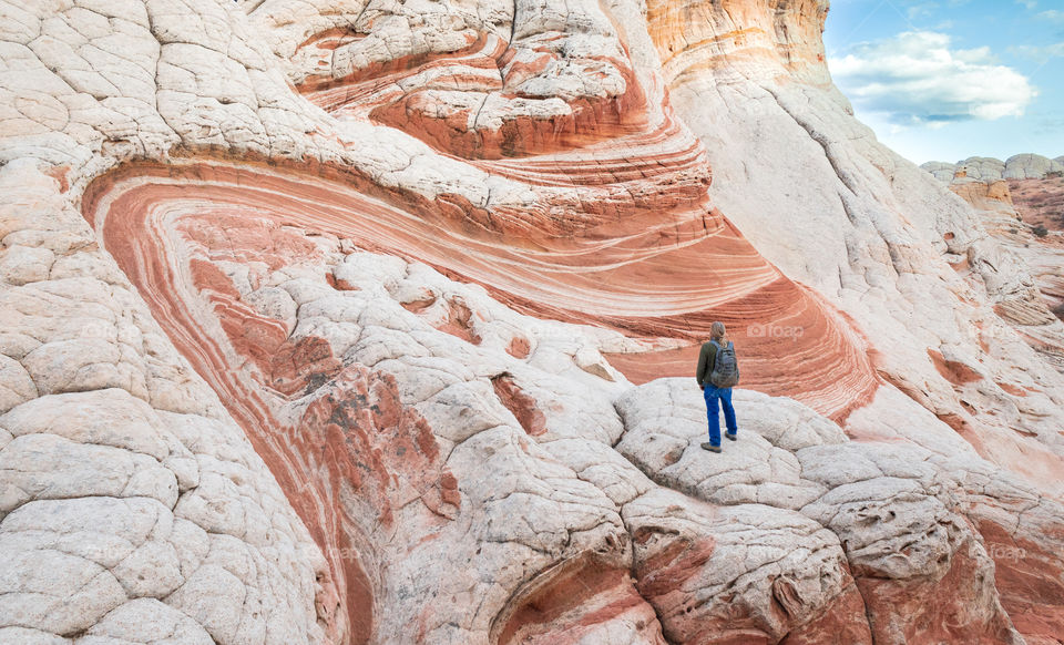 A man looks at an interesting swirling rock formation in the desert.