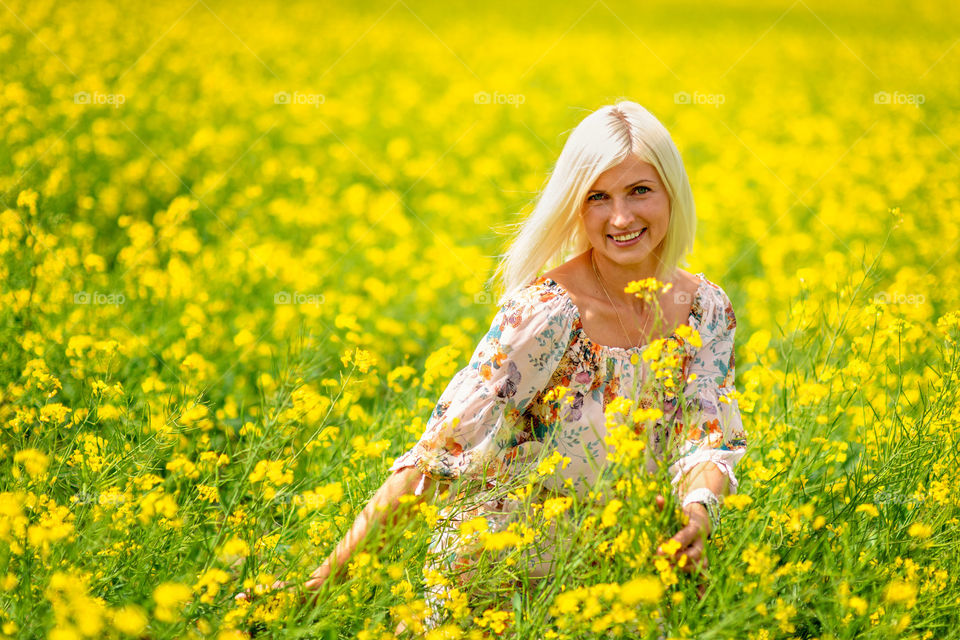Soft, selective focus. Beautiful, attractive, blond woman in a yellow flower meadow.