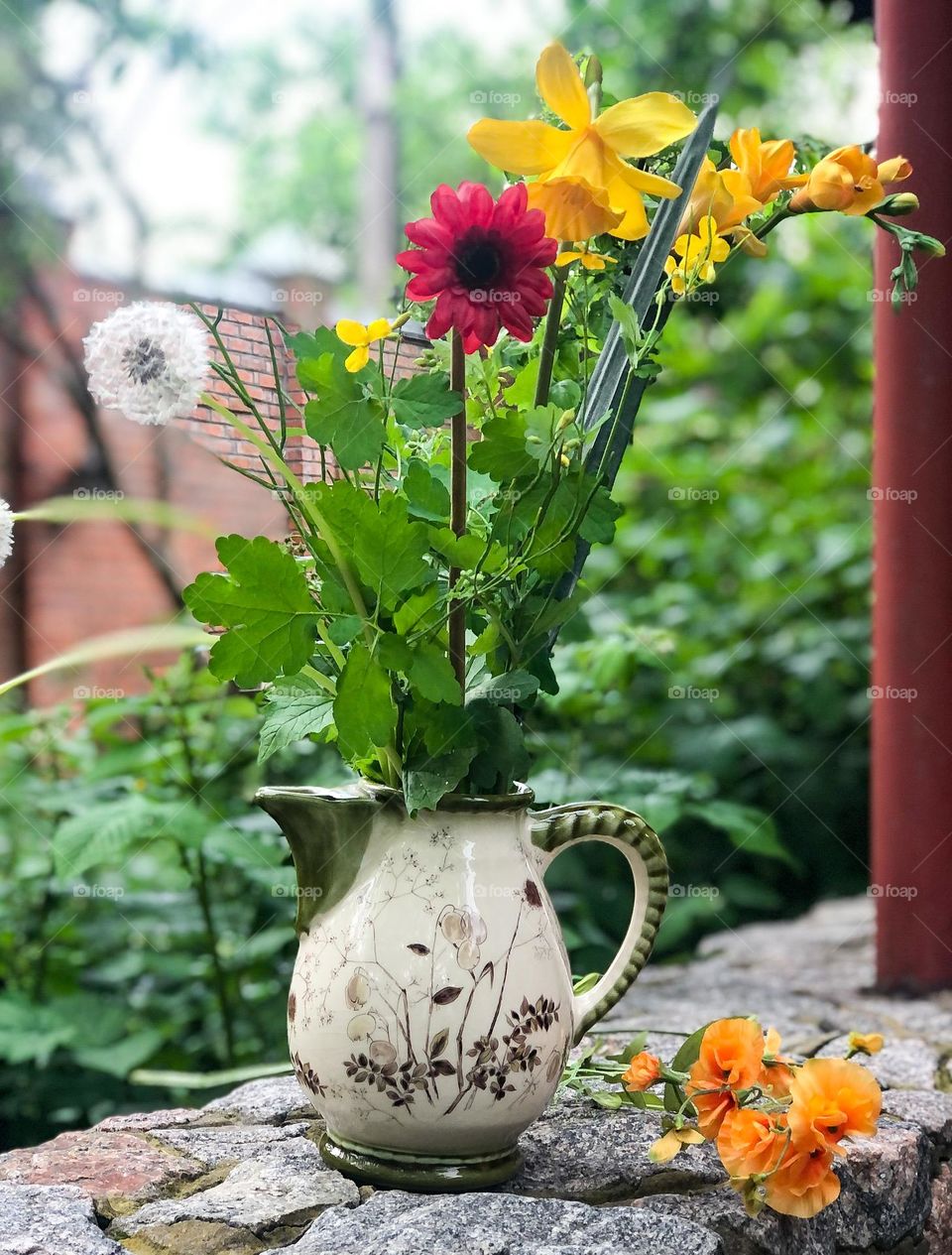 Bouquet spring flowers and herbs in old green pottery kettle 