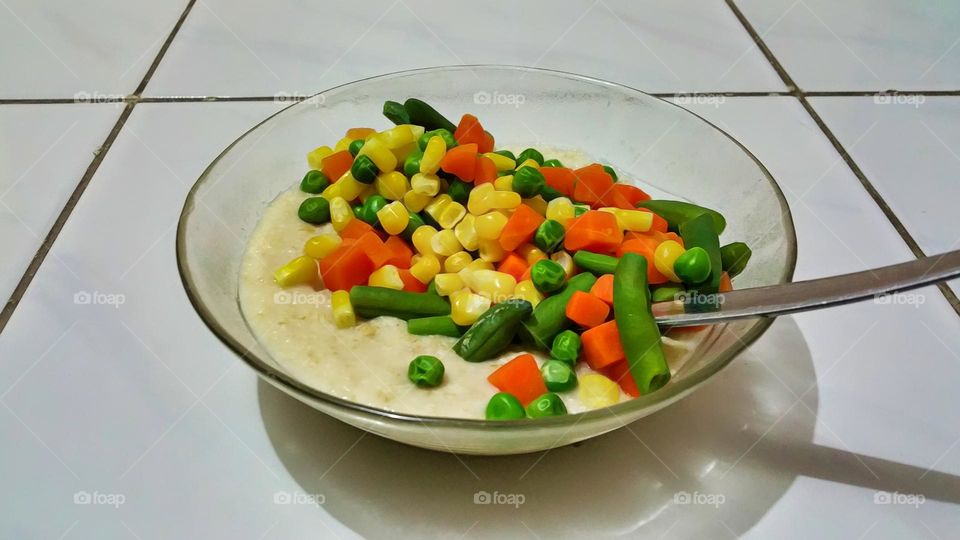 healthy menu: plate of oats topped with small slices of carrots, chickpeas, peas, and carn kernels