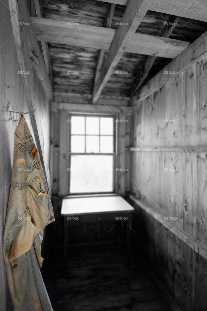 Tattered bluejeans hang on the wall in the cottage by the window
