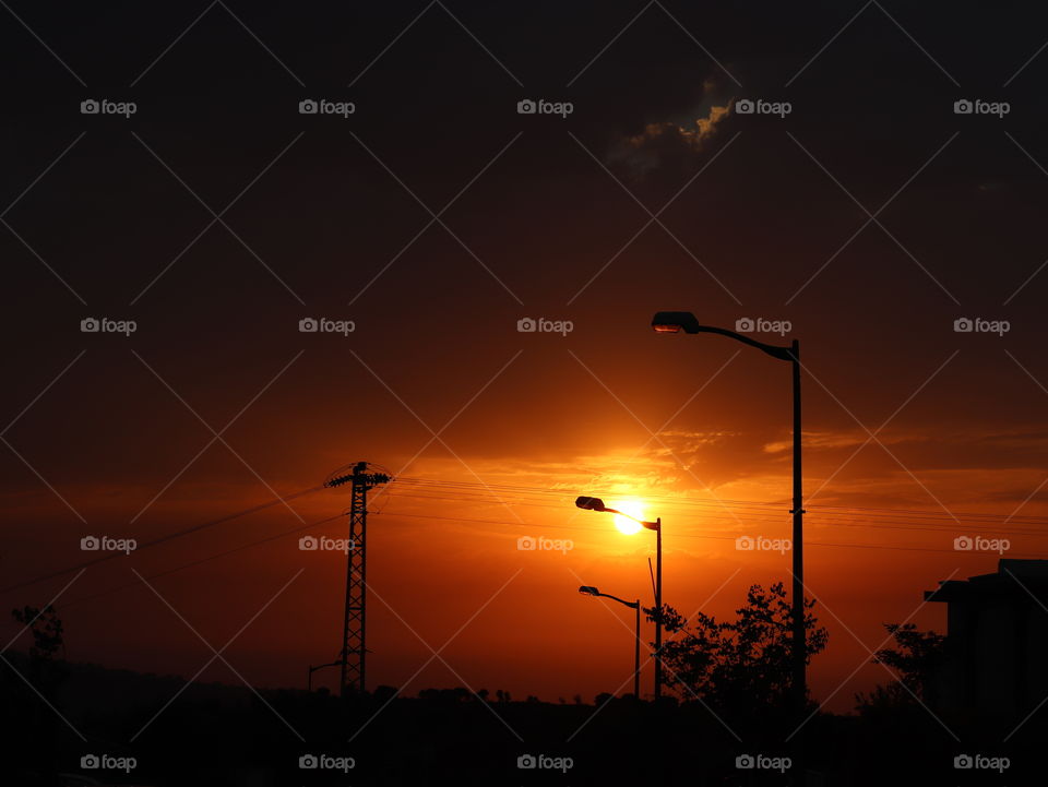 Red and orange sunset with black clouds and electric polls