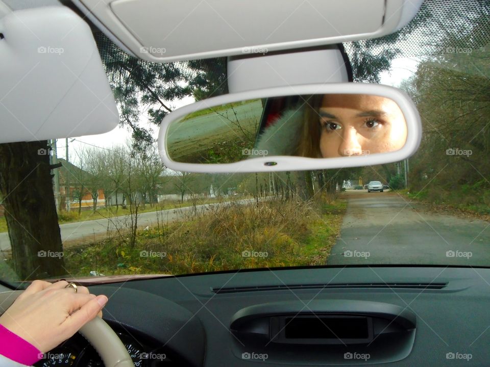 Woman face in the car mirror while driving