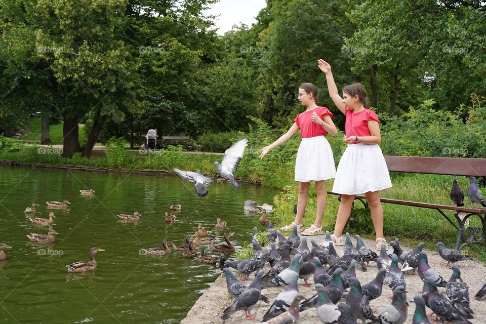 Two girls feeding pigeons in the city park