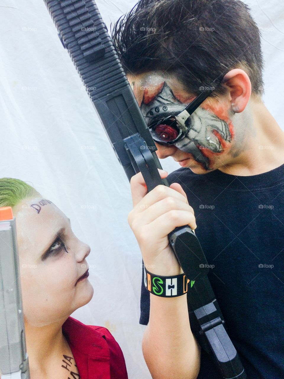 Man and woman with face paint holding gun in hand