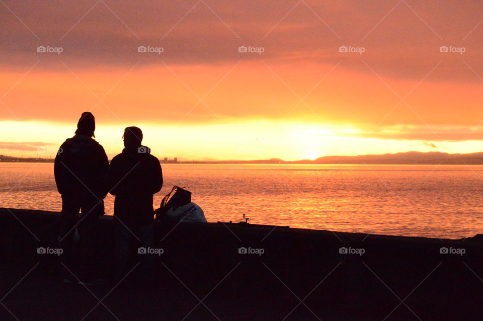 Two people standing against sea