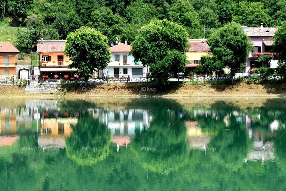 country side with houses and trees reflecting in water lake