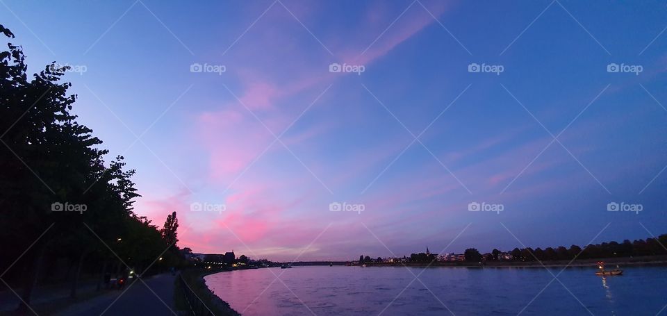 Promenade by the river Rheine in Bonn with a beautiful pink sunset sky.