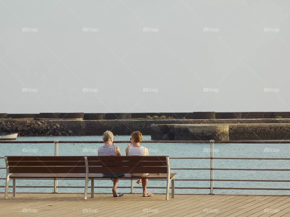 women sitting resting sitting on a bench overlooking the sea