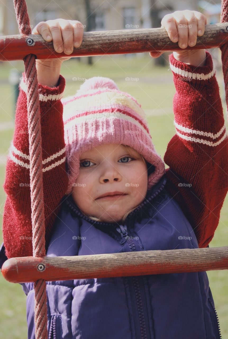 Girl climbing. A girl climbing a rope lather at the playground