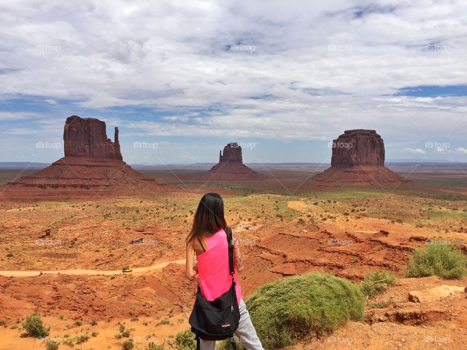 A woman with a pink singlet is looking around where is the beautiful Monument valley tribal park landscape
