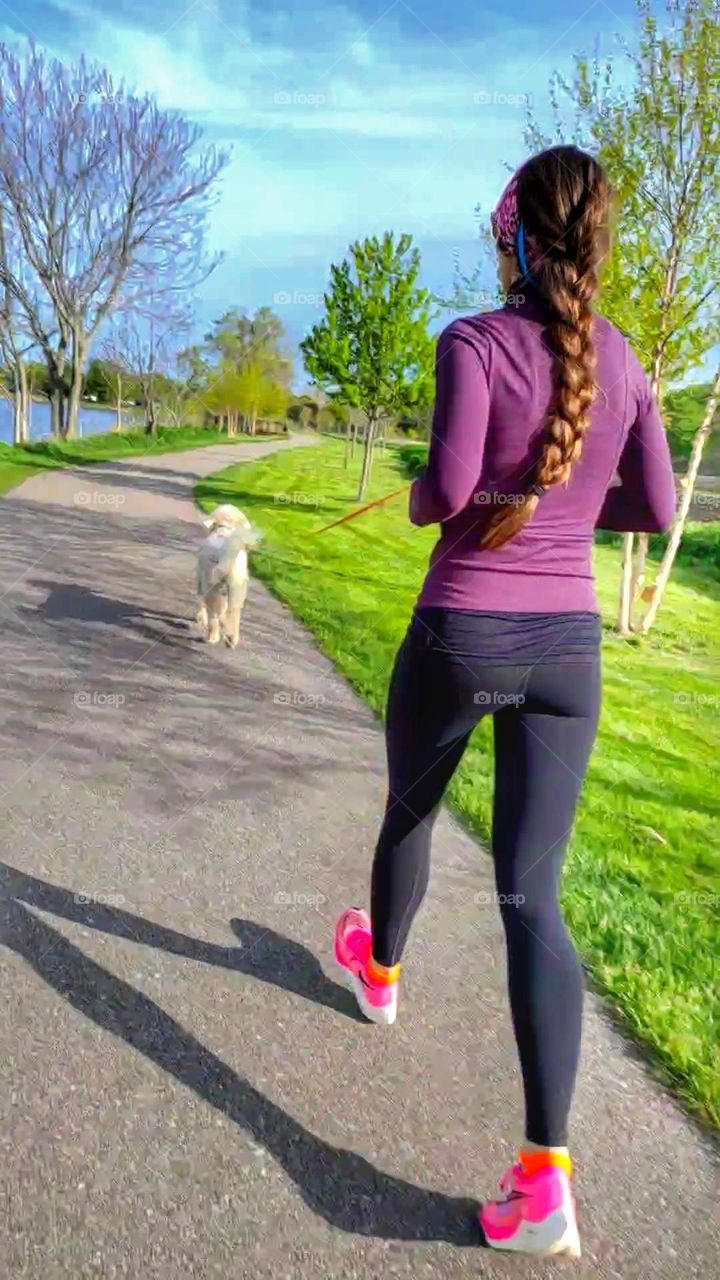 woman in yoga pants walking dog in the park