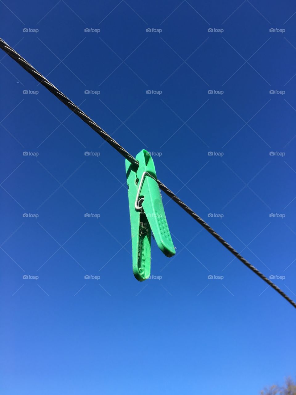 Stark minimalistic contrast, one plastic clothespeg hanging on clothesline 