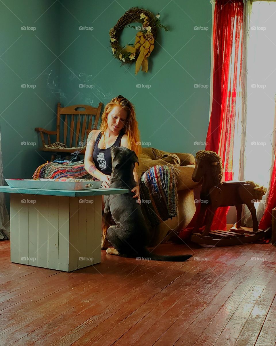 red Haired girl looking lovingly at large black dog in a homey space