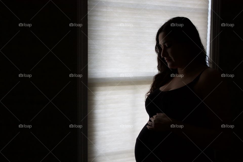 Pregnant woman standing in front of window