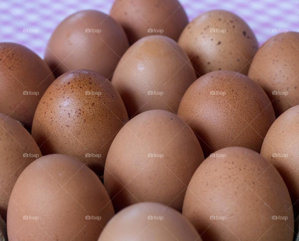 A batch of fresh eggs against a pink gingham tablecloth