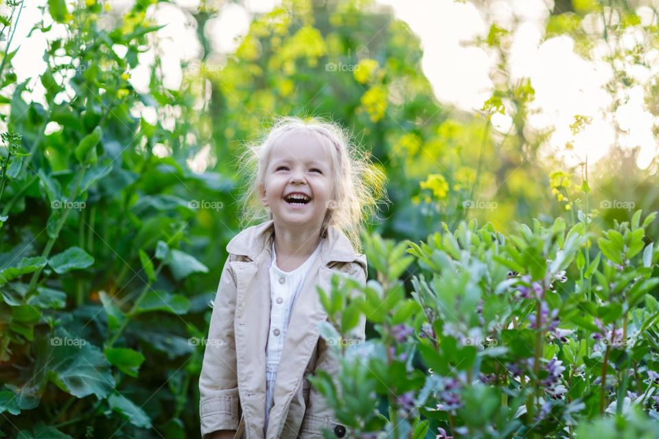 Candid lifestyle portrait of happy little Caucasian girl with blonde hair outdoor 