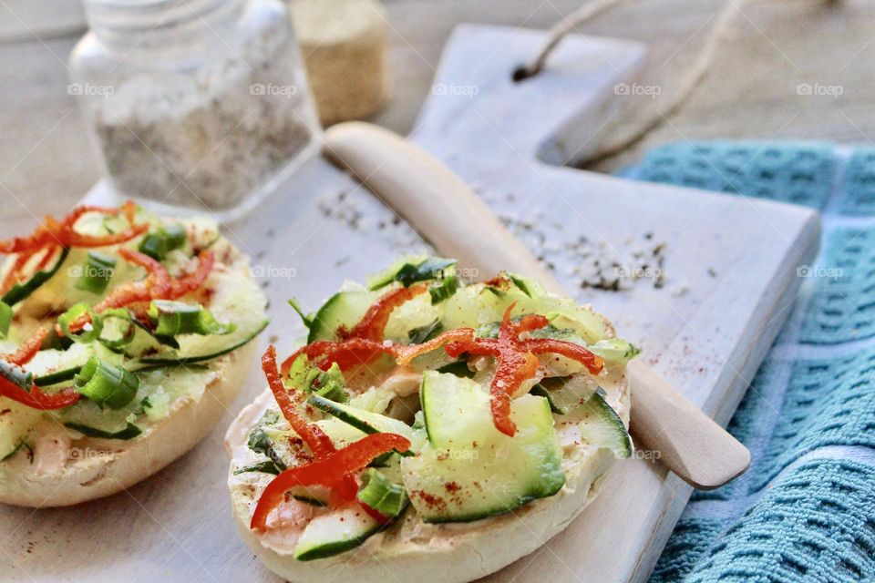 Salmon spread with thin sliced cucumber, red pepper, and green onion on a toasted bagel 🥯