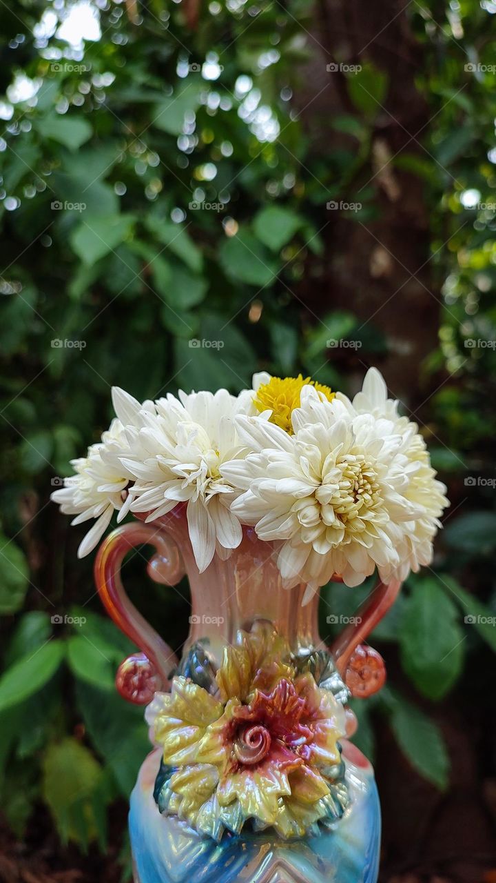 Beautiful white flowers in a colourful flowerpot with a flower sculpture, Flowers in a vase, colourful vase, white flowers in a vase