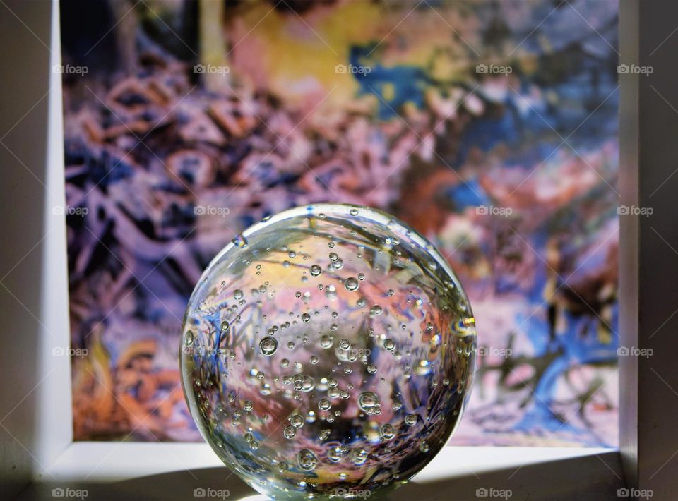 crystal clear glass ball with bubbles on a white surface with corful graffiti background