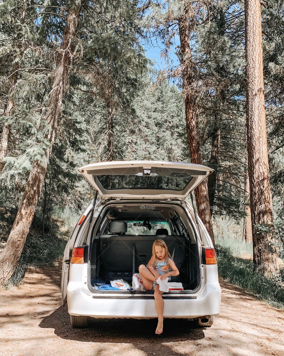 Girl in cab of van cleaning sand off feet