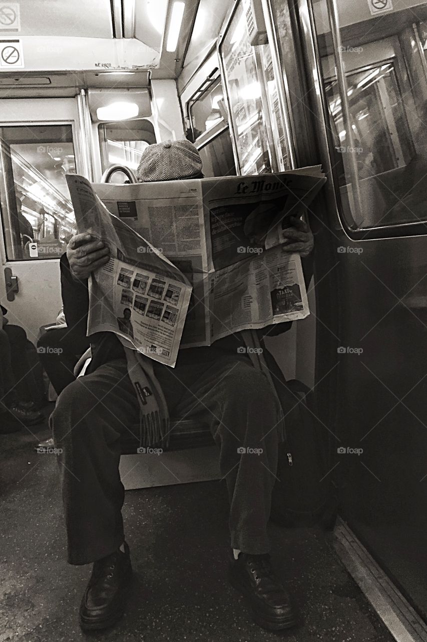 Old man reading newspaper on the subway 