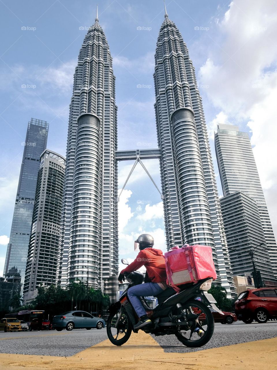 A food panda rider infront ot Petronas Twin Towers in Kuala Lumpur, Malaysia