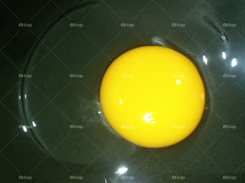 One yellow egg/egg yolk and egg white in  a black pan