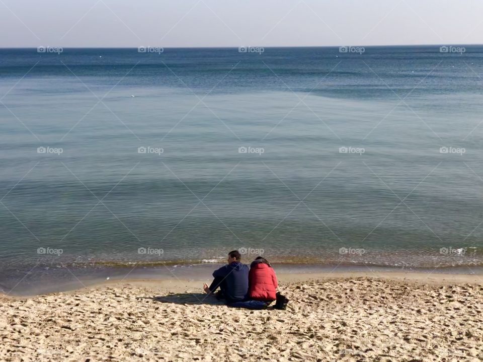 A couple is sitting in the beach 