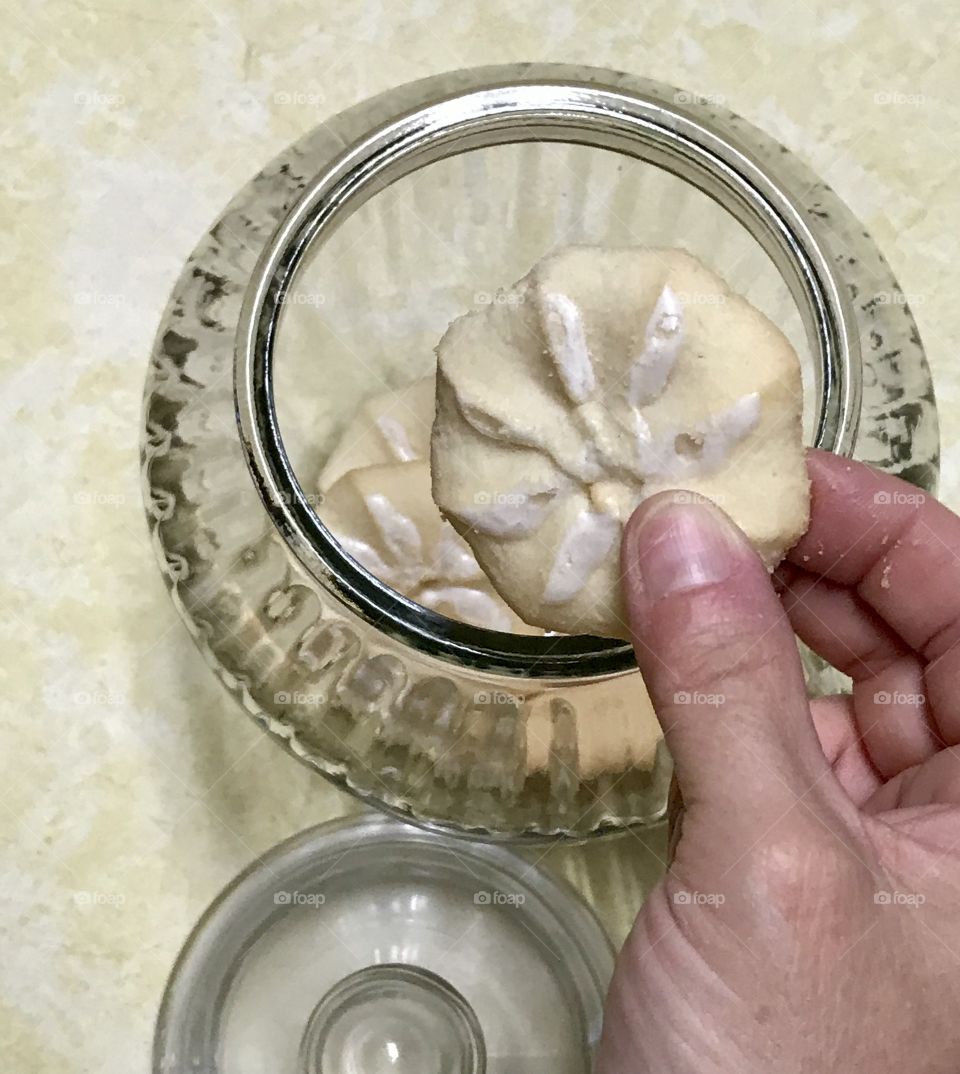 Person taking cookie from a cookie jar