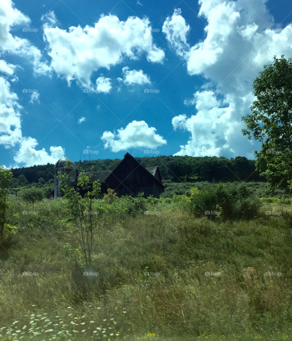 Beautiful landscape with amazing sky and grass with a rustic building in the distance. 