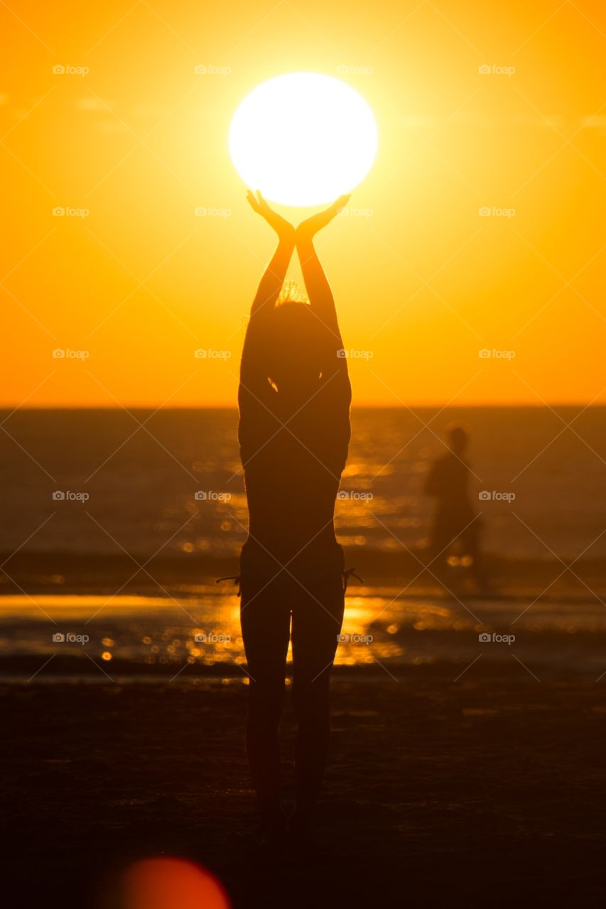 Little girl playing with the sun during sundown