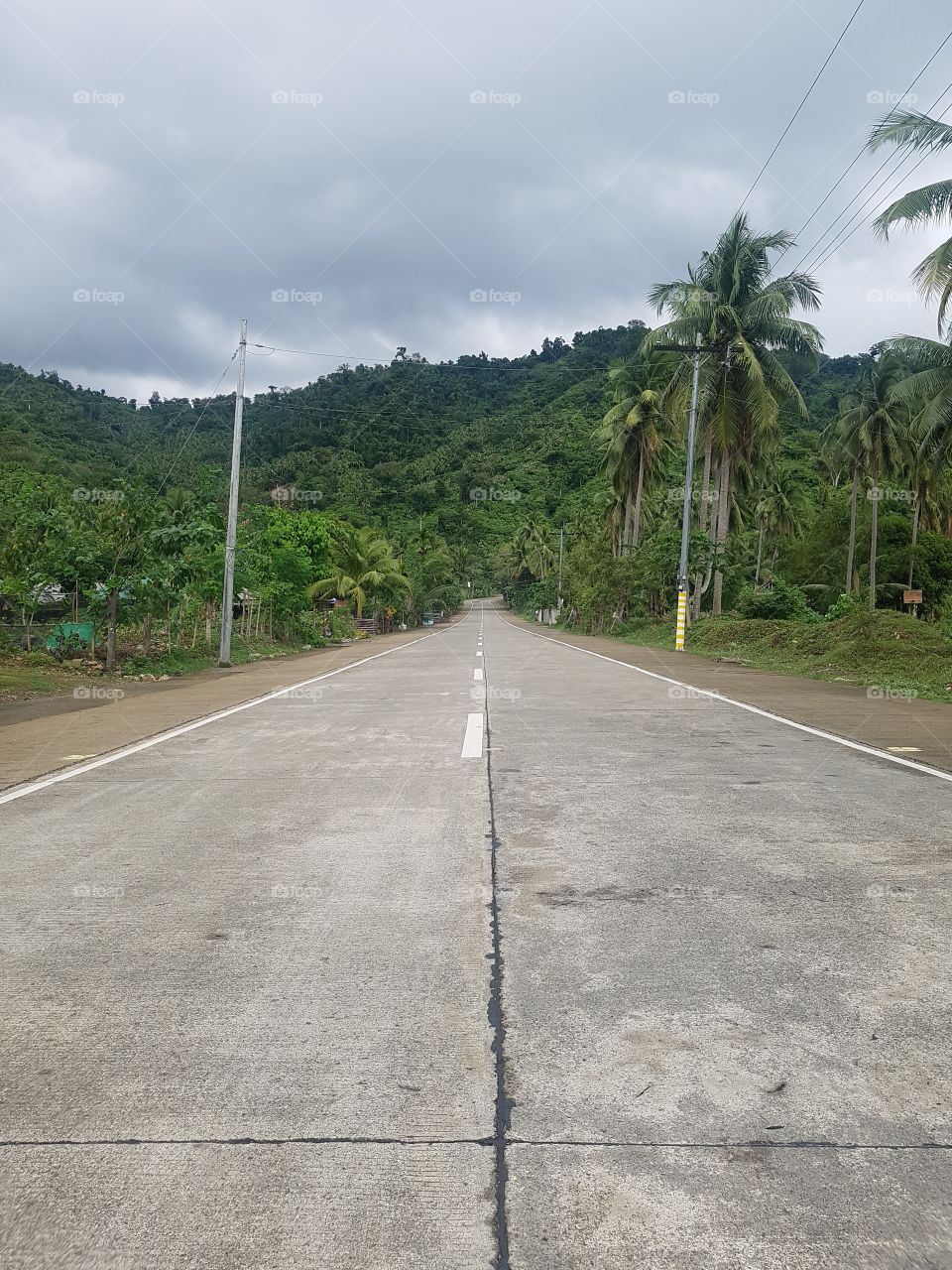 lonely empty road with cloudy sky and mountainous background