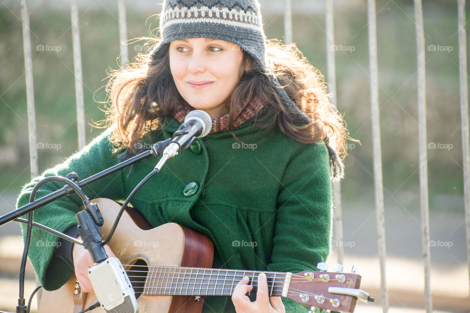 Young Smiling Musician Woman Playing The Guitar And Singing On The Street In Winter
