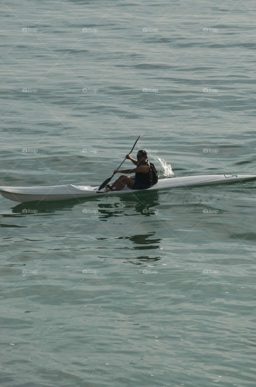 A young man kayaks on the Pacific Ocean in Laguna Beach California.