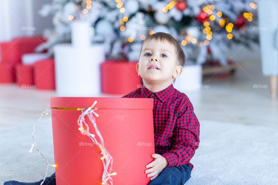 boy and gift box next to christmas tree