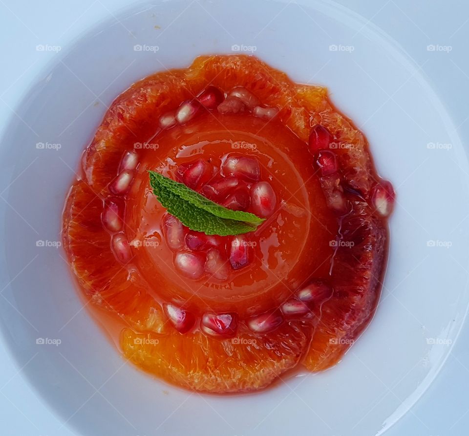 Delicious, fresh orange jelly with pomegranate in a white plate