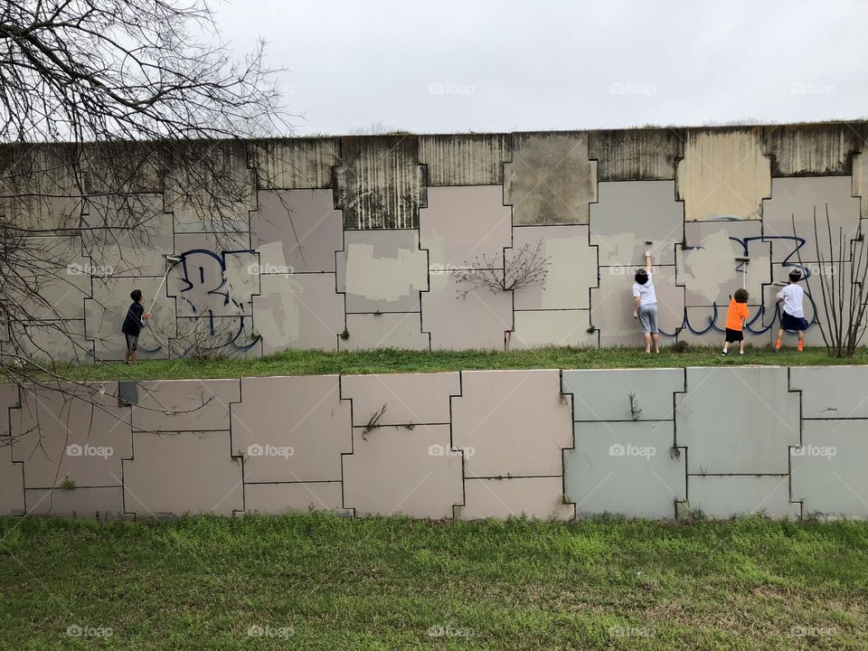 Kids covering over graffiti and improving their community. 