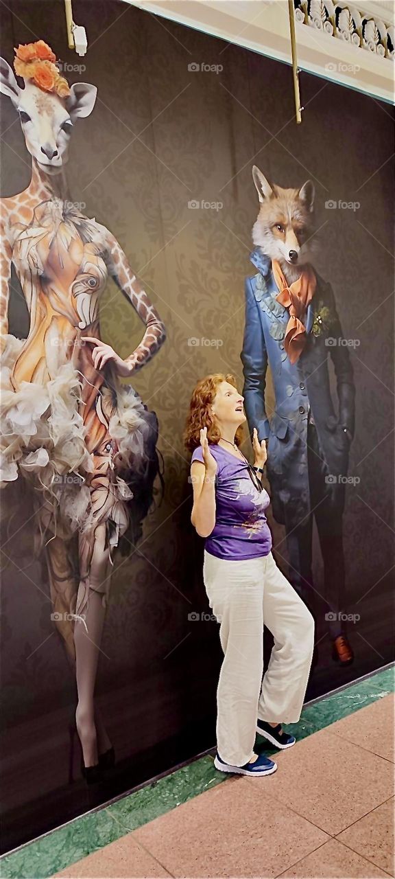 These elegantly attired chimeras, the giraffe ballerina and the clever fox adorn the foyer of “das Schloss”, “the Castle”, a multistory shopping mall in “Berlin”, Germany in the “Steglitz” neighborhood. 2024. Hypnotic Productions