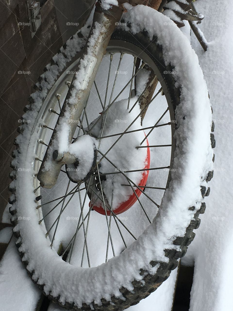 Last snow of the season in Virginia outlines a motorcycle wheel.