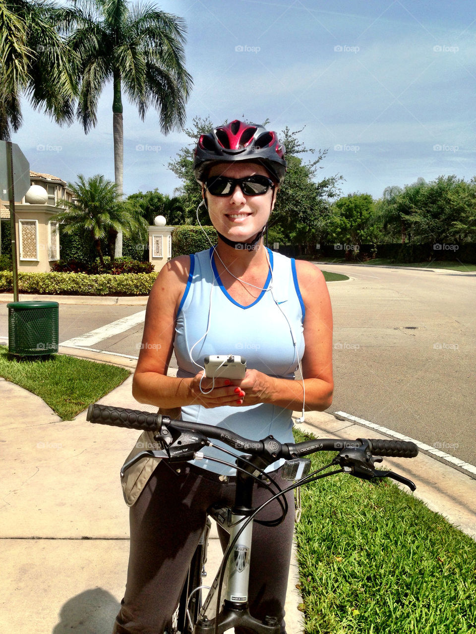 Woman on bicycle with helmet and headphones smiling