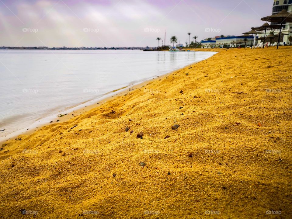 On the banks of the Suez Canal. A sandy beach on a rainy day, with a resort in the backdrop. 