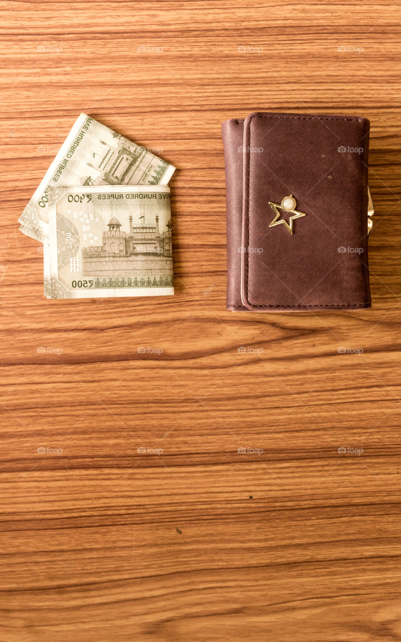 Indian five hundred (500) rupee cash note in brown color wallet leather purse on a wooden table. Business finance economy concept. High angel view with copy space room for text on front side of image