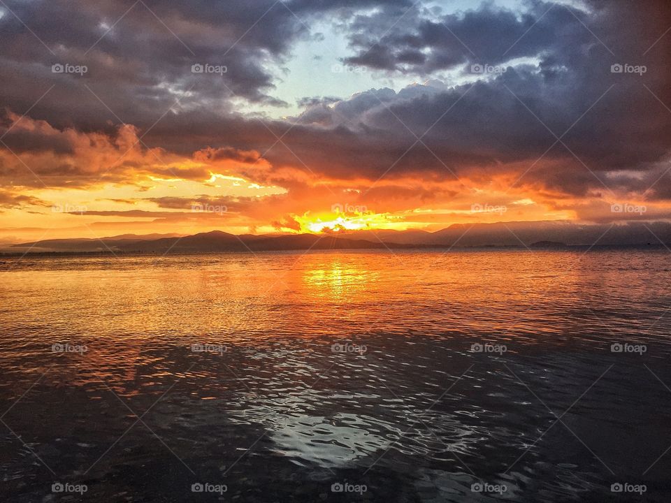 Just our father Sun burning as it rises from the depths of the other side reflecting its face and flames from the waters of one of the oldest lakes in the world