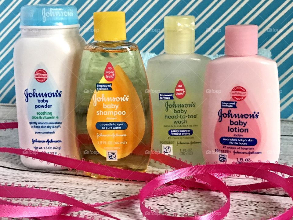 Johnson and Johnson baby lotion, shampoo, head to toe wash and powder on a blue and white background with a pink ribbon 